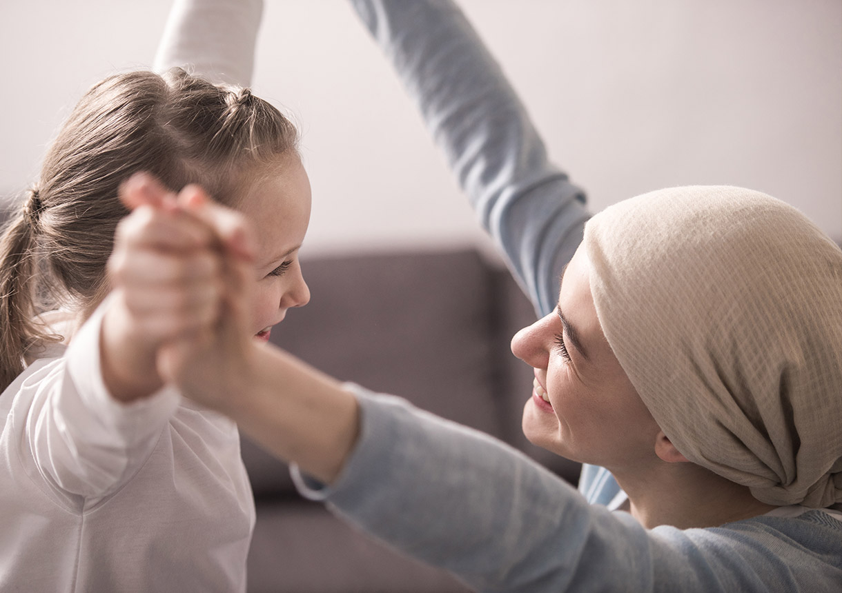 Frau mit Krebs spielt mit Kind.