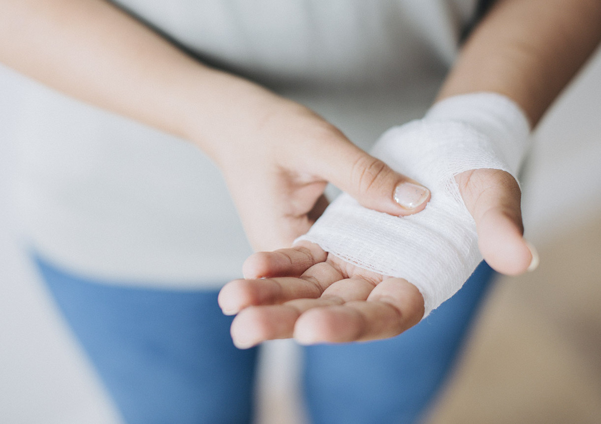 Frau versorgt Ihre Wunde mit Verband.
